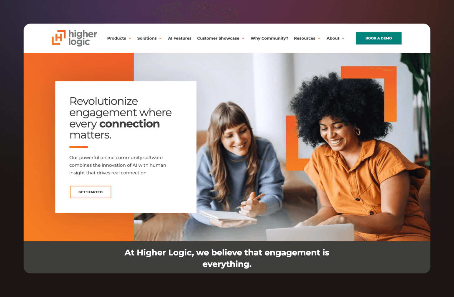 Two women collaborating at laptop, one in blue taking notes while the other in orange looks on smiling